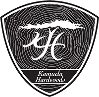 Kamuela Badge Logo has the K and H that form the tree trunk with bushy leave on top and the words Kamuela Hardwoods under it all incased in a badge shape with wood grain as the background
